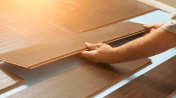 A Fullerton Paint & Flooring technician installing wood flooring in a room.