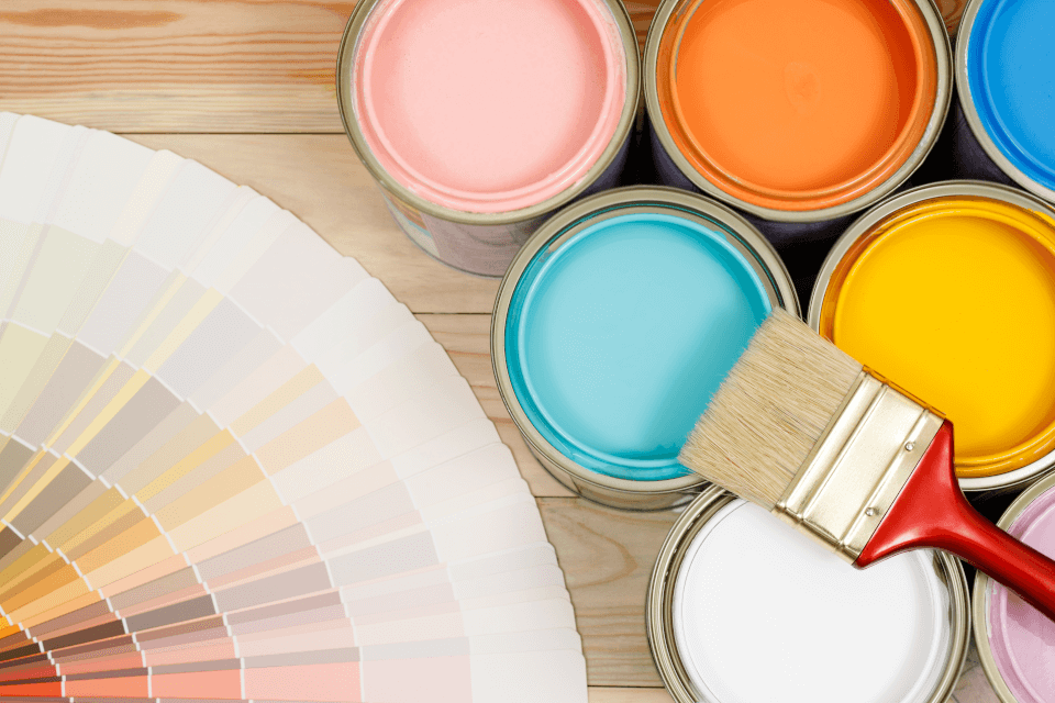 Paint colors and brushes neatly arranged on a wooden table, ready for a interior decorating.